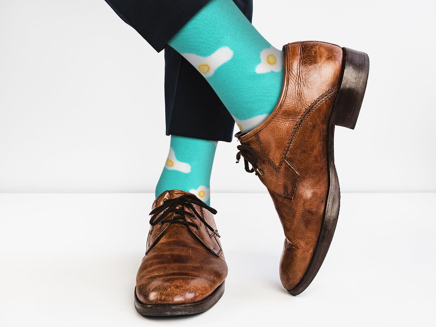 Brown dress shoes and turquoise socks with cloud design on a white background