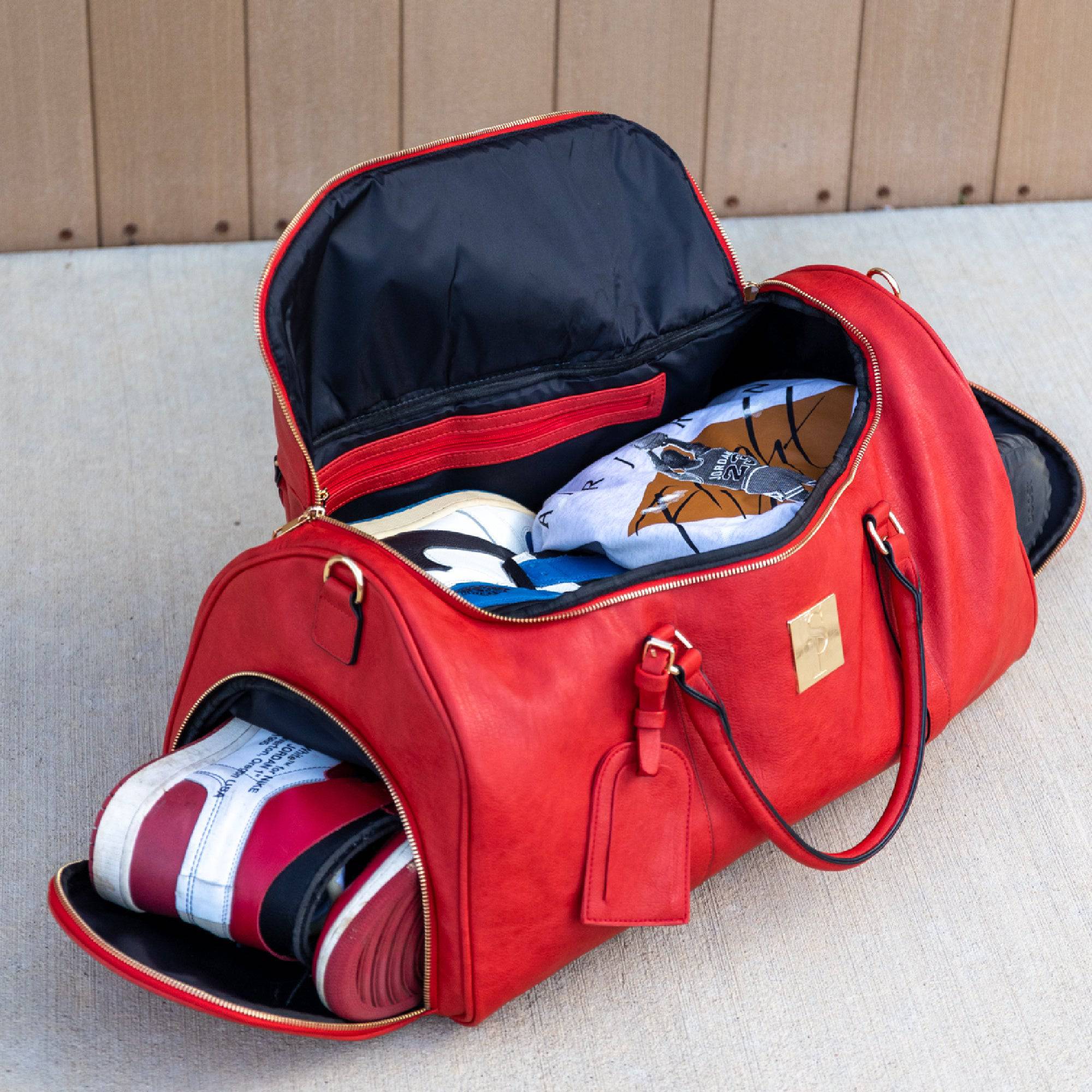 Red duffel bag with shoes and clothing items on a light surface.
