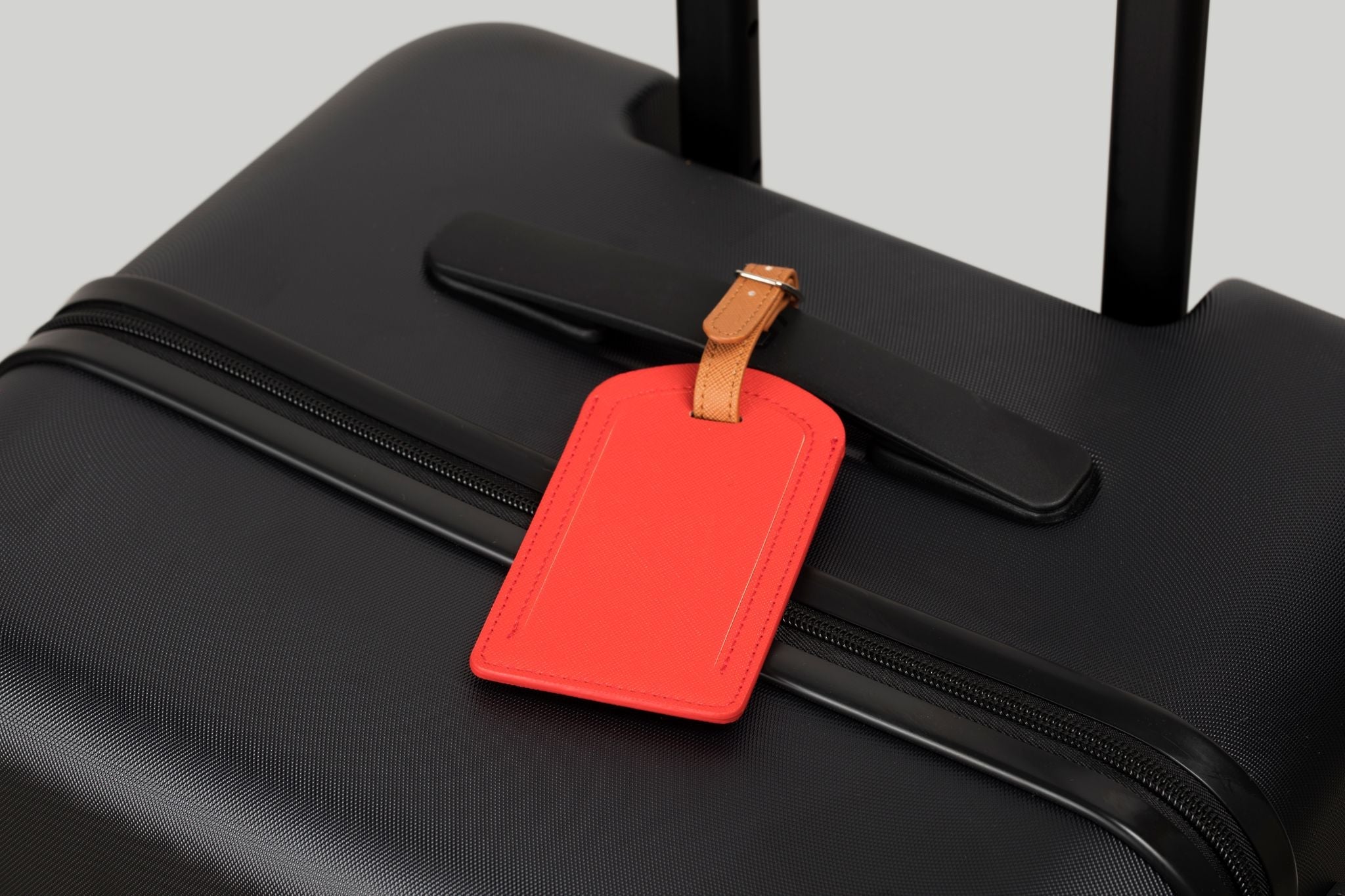 Black suitcase with a red luggage tag attached
