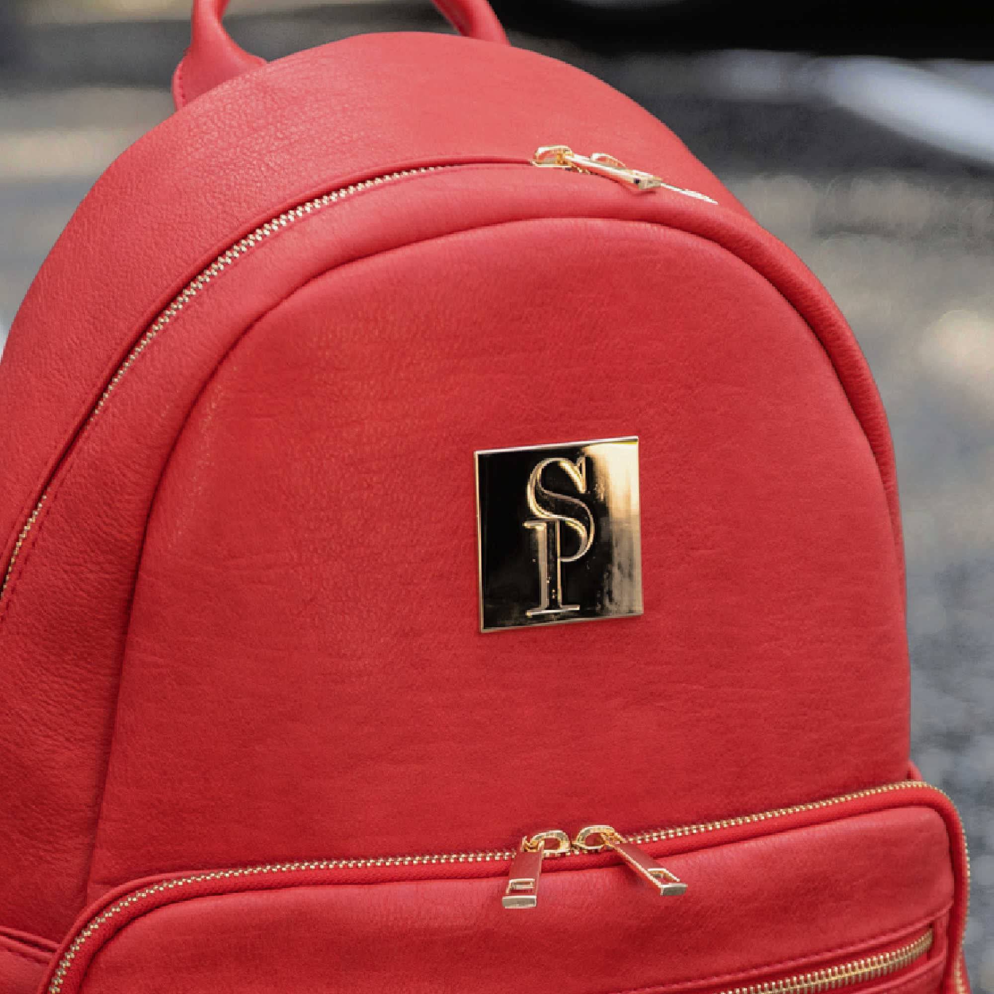 Red backpack with a gold logo on a blurred background