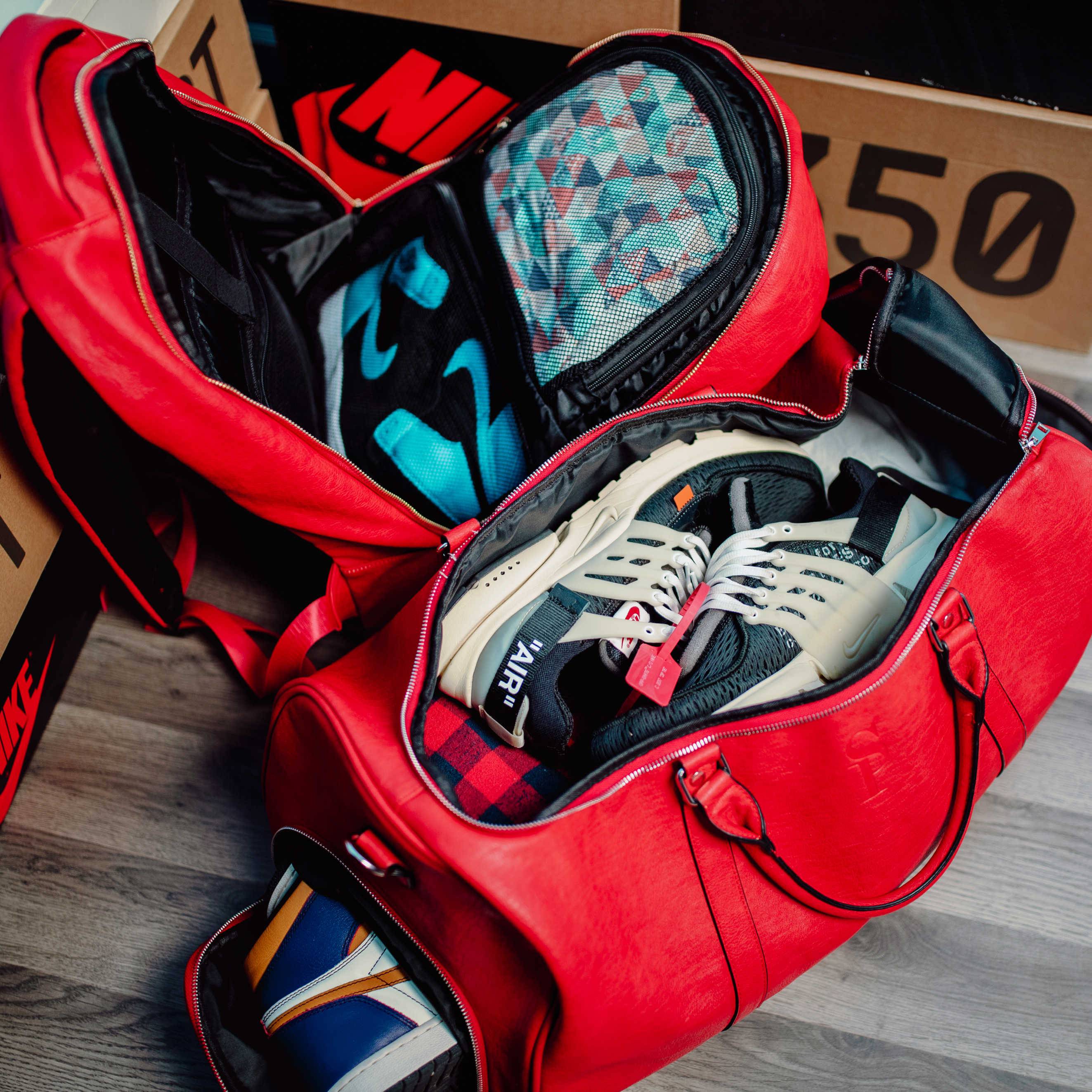 Red duffel bag with shoes and socks on a wooden floor