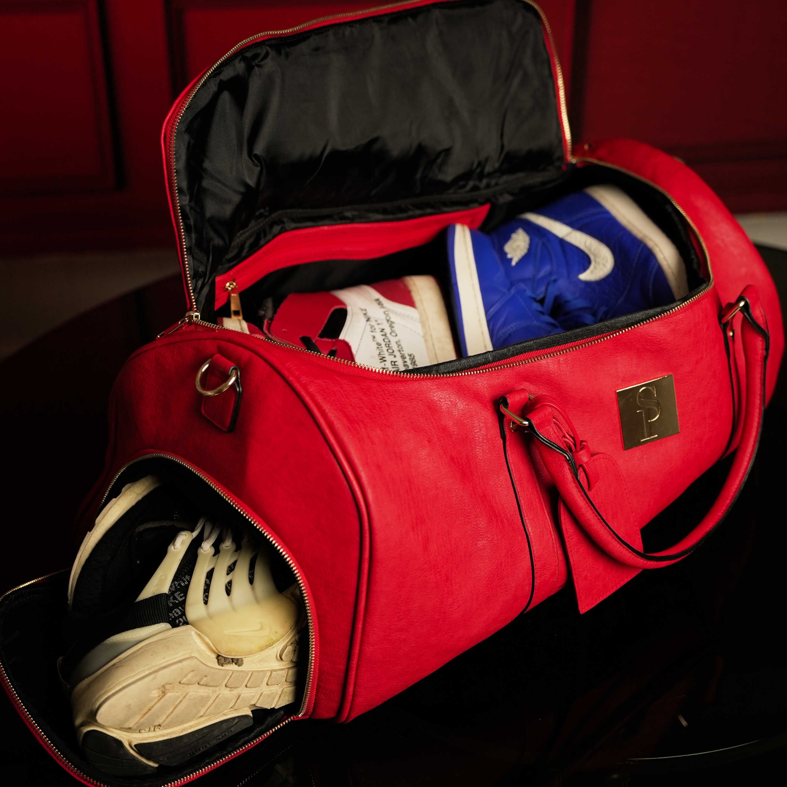 Red duffel bag with sneakers inside on a dark background