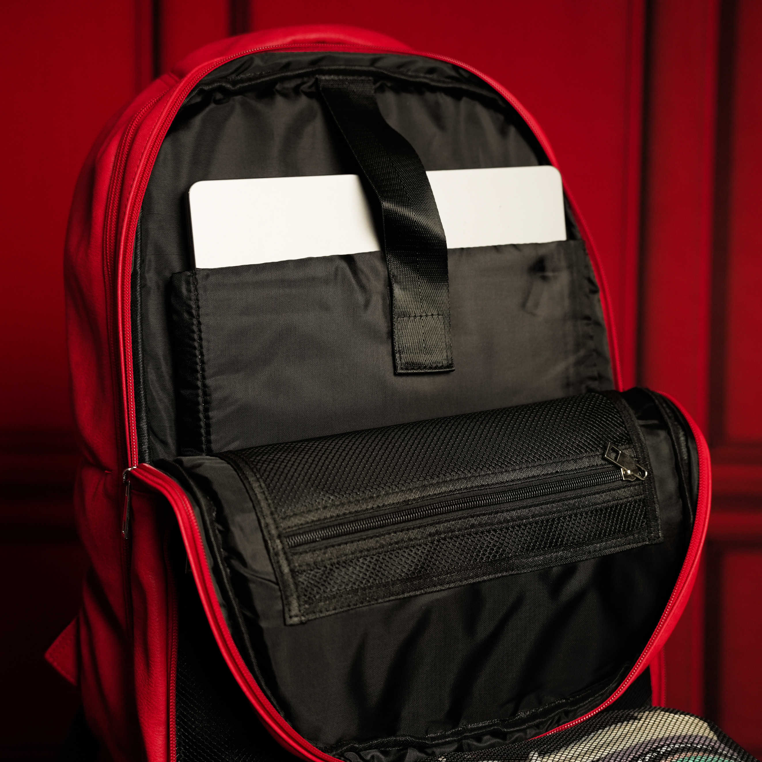 Red and black backpack with open compartment showing a white card on a red background