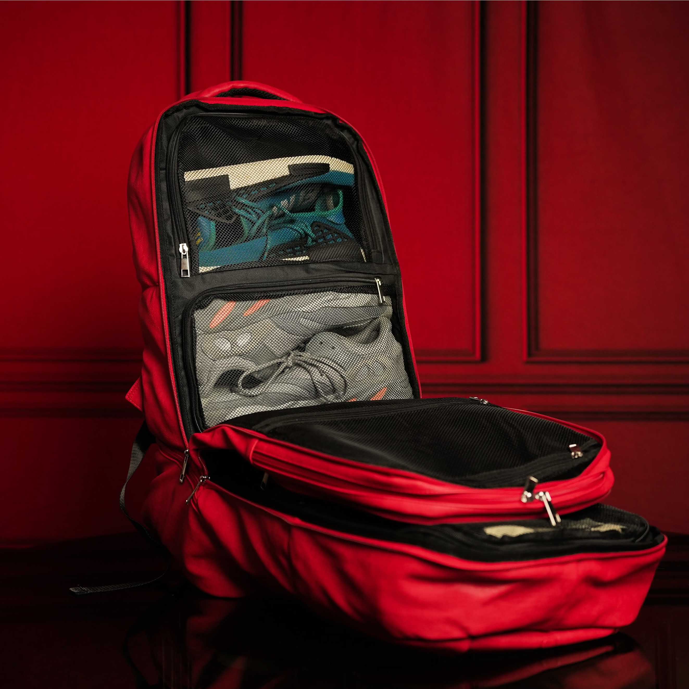 Red backpack with compartments open against a red background