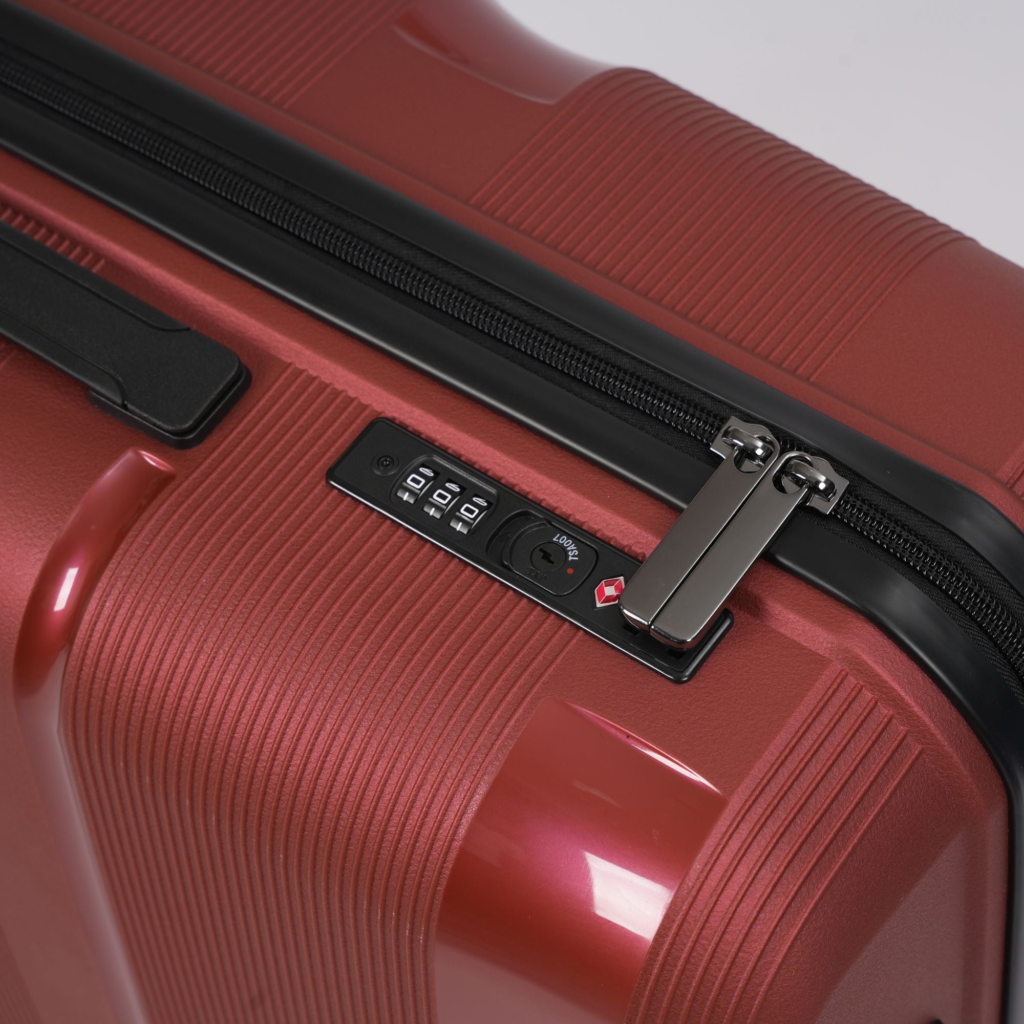 Close-up of a red suitcase with a zipper and label on a white background