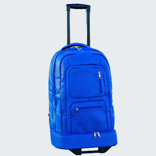 Blue rolling backpack on a sidewalk with a building and greenery in the background