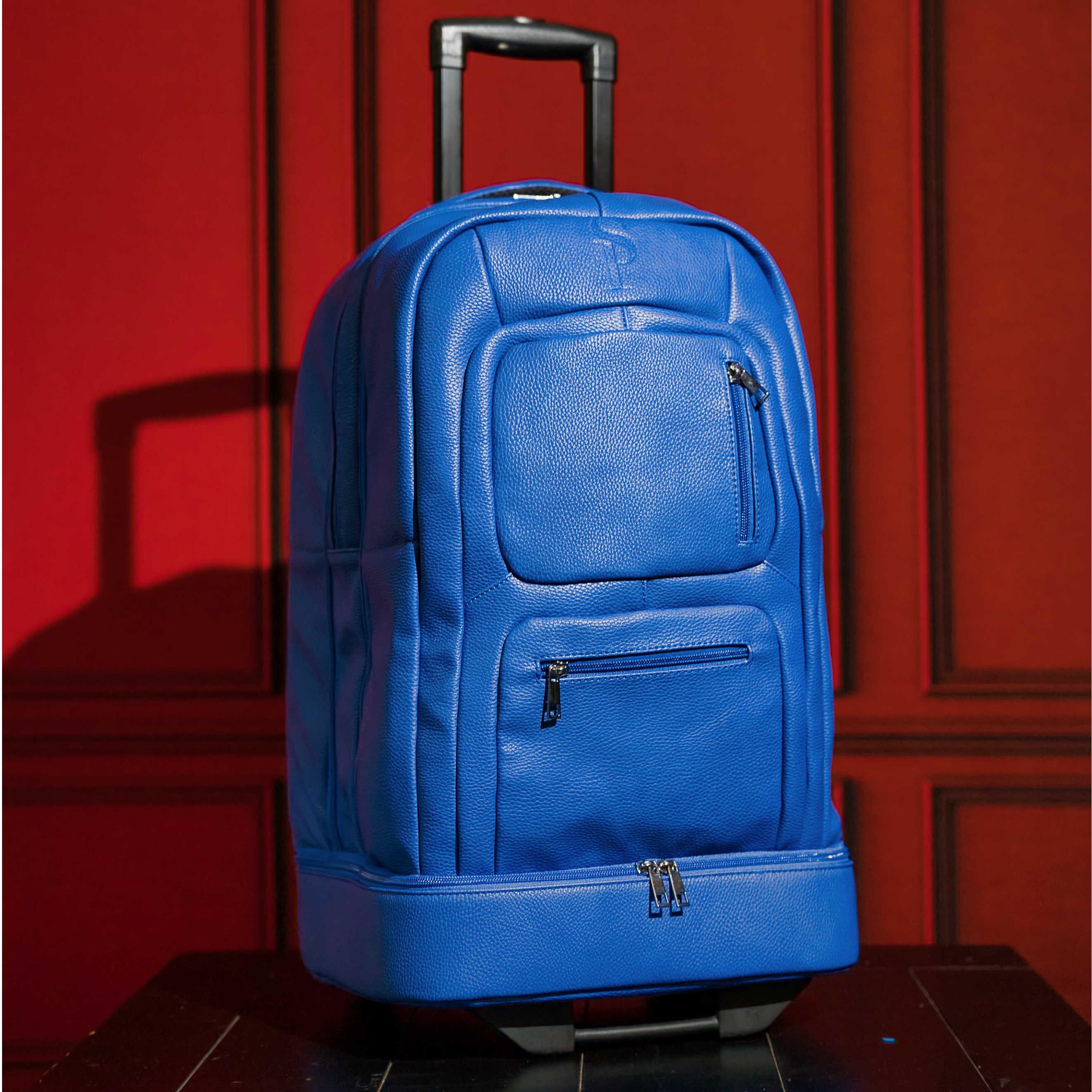 Blue rolling backpack against a red wall