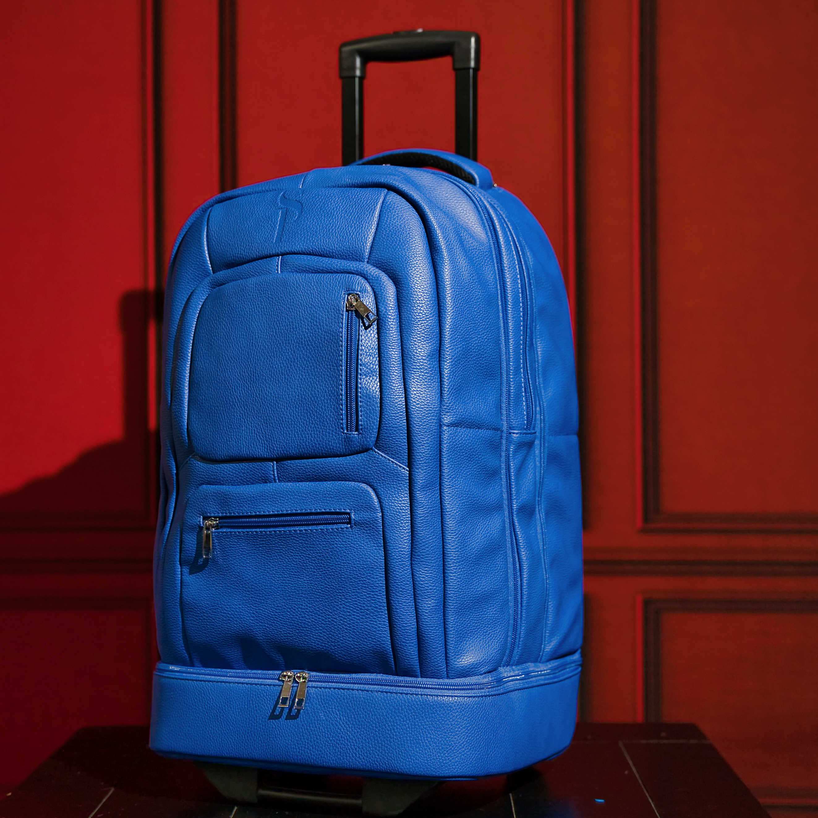 Blue rolling backpack on a red background