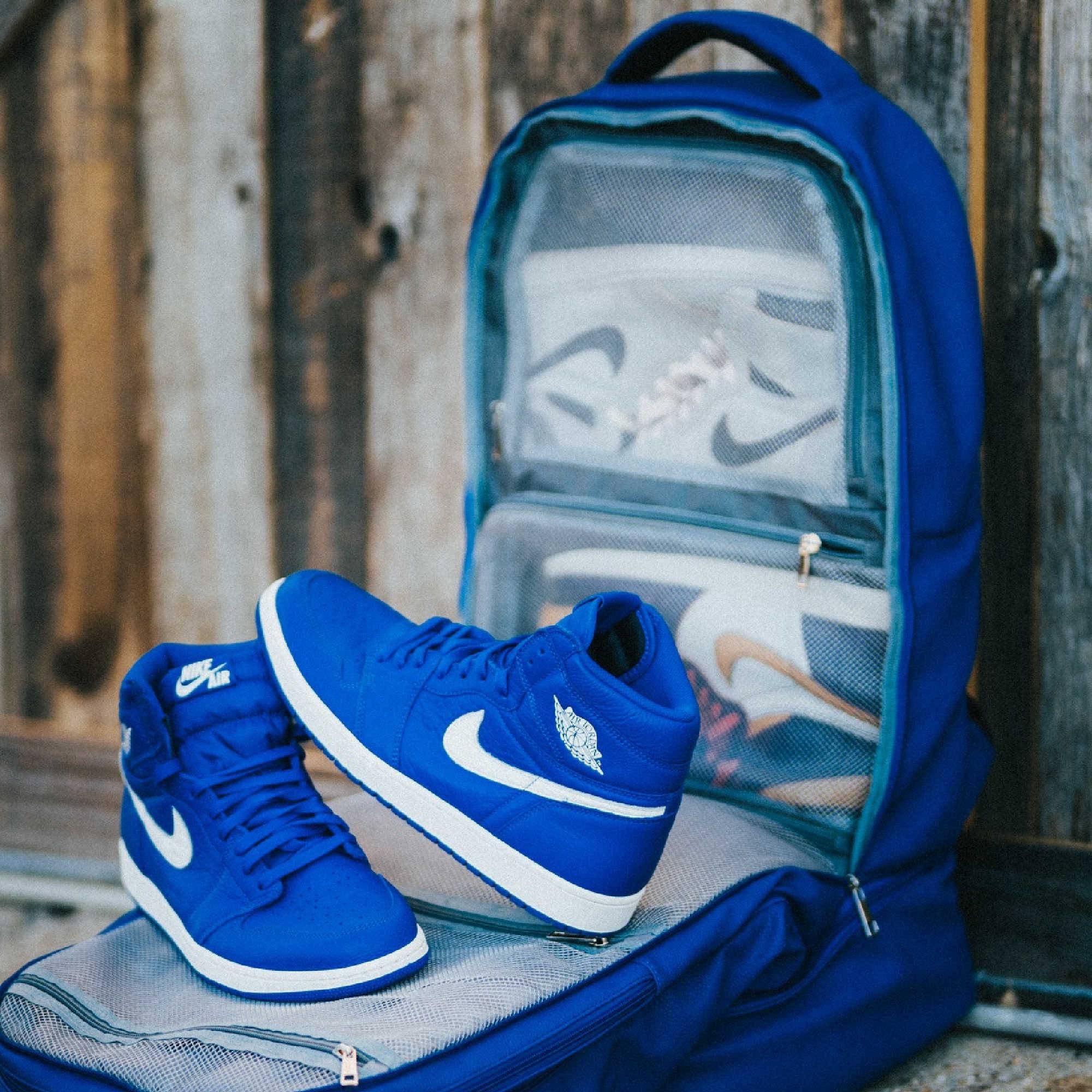 Blue sneakers with white swoosh logo on a blue backpack against a wooden background