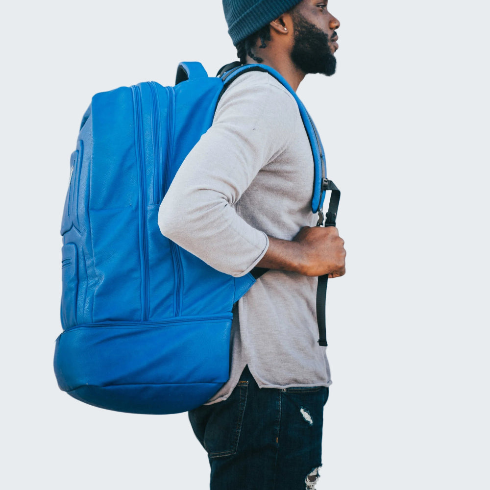 Person wearing a blue backpack in front of a white door