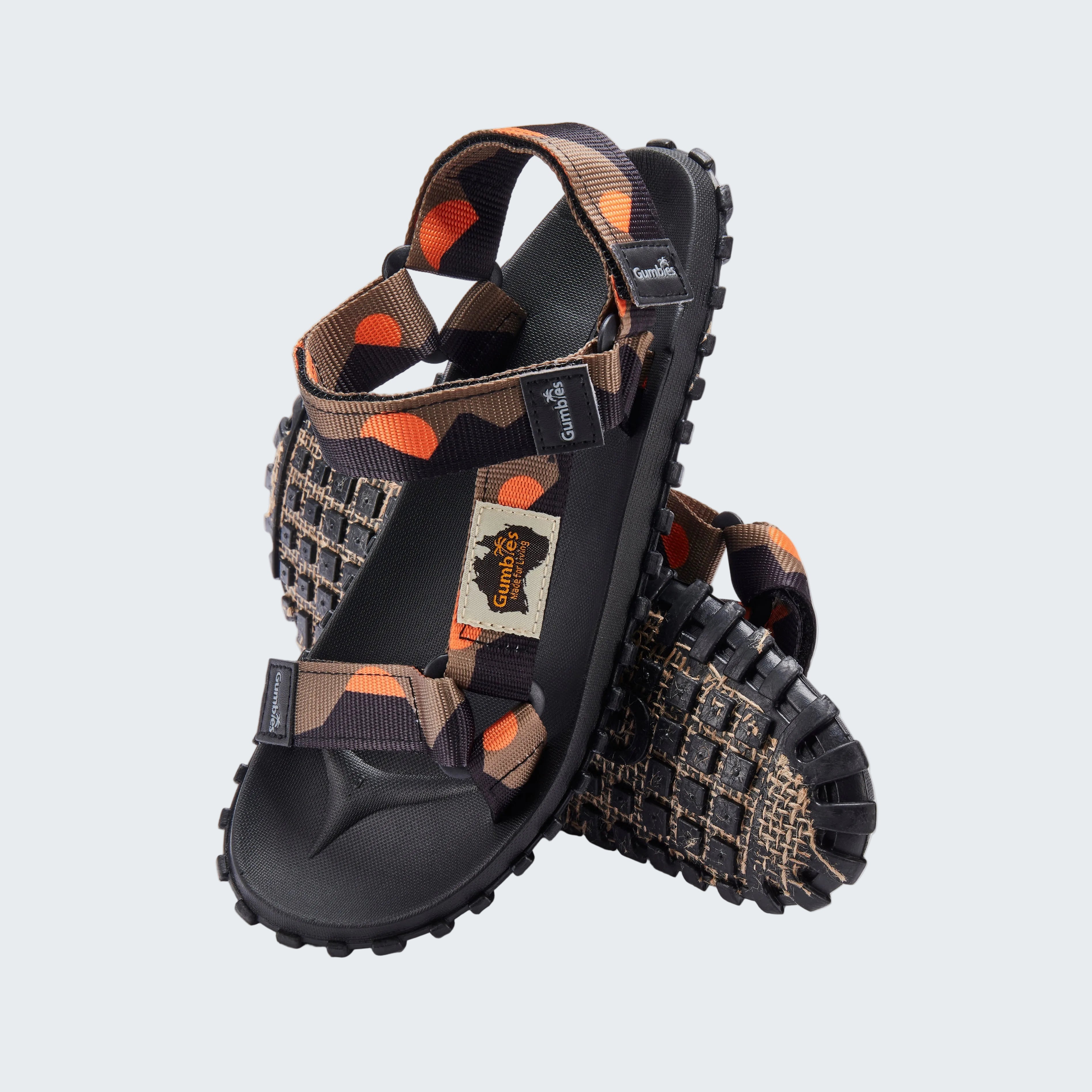 Pair of black and brown sandals with orange accents on a white background
