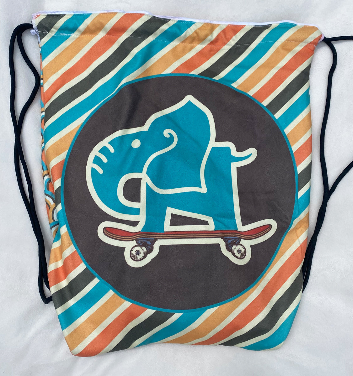 Drawstring bag with colorful stripes and a graphic of a dog on a skateboard on a white background