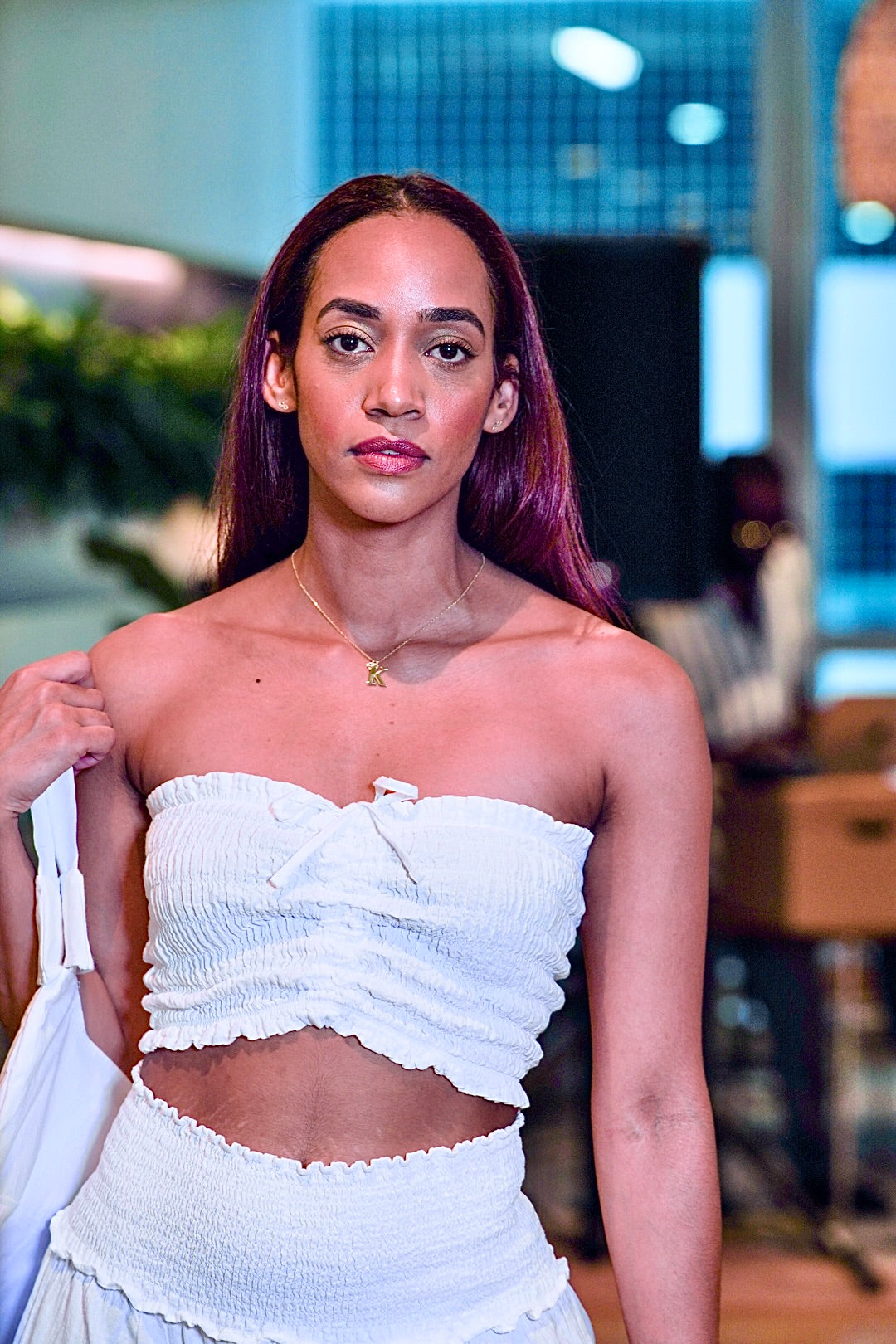 Woman wearing a white strapless top with a blurred indoor background