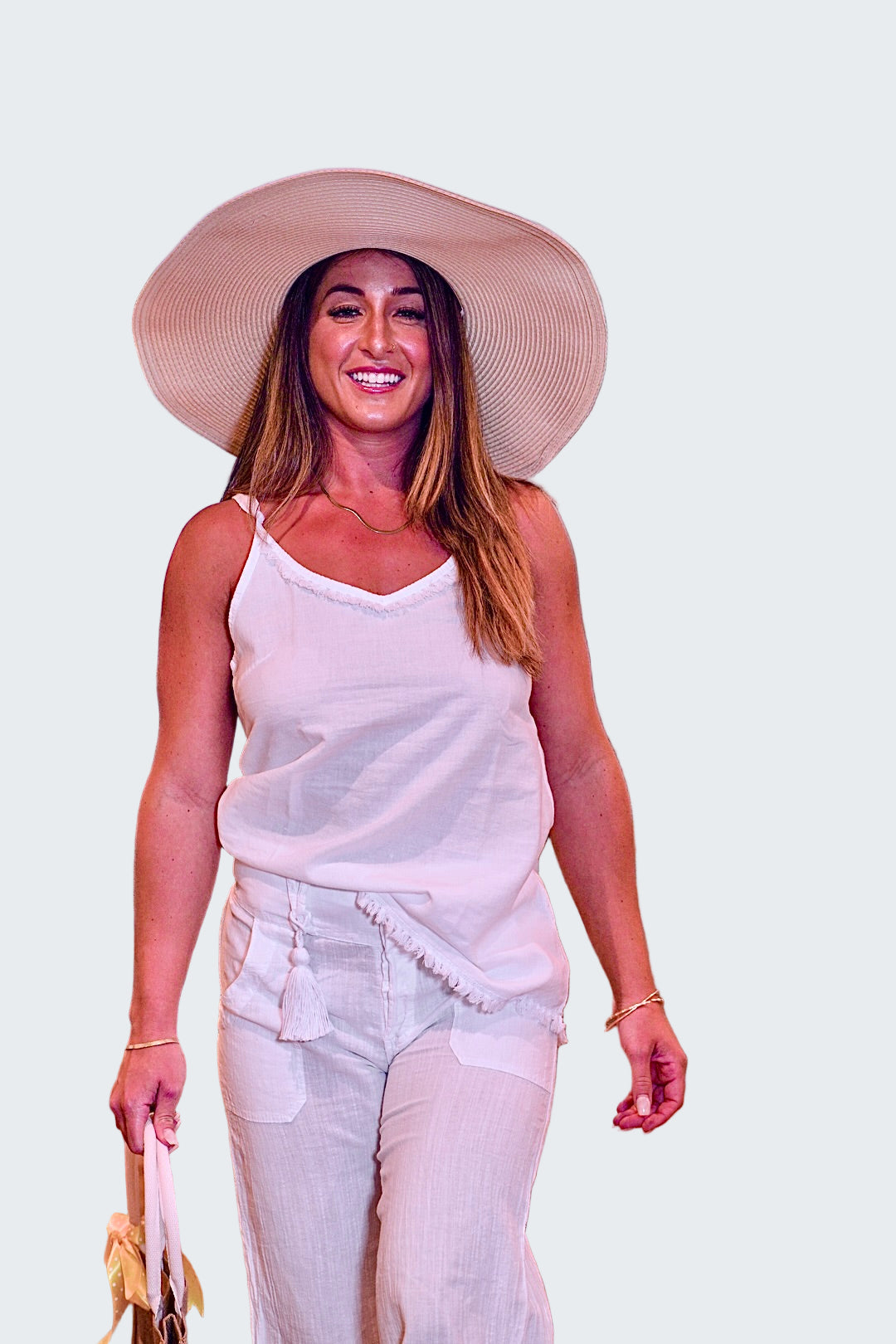 Woman in a white outfit and large hat walking indoors with blurred background