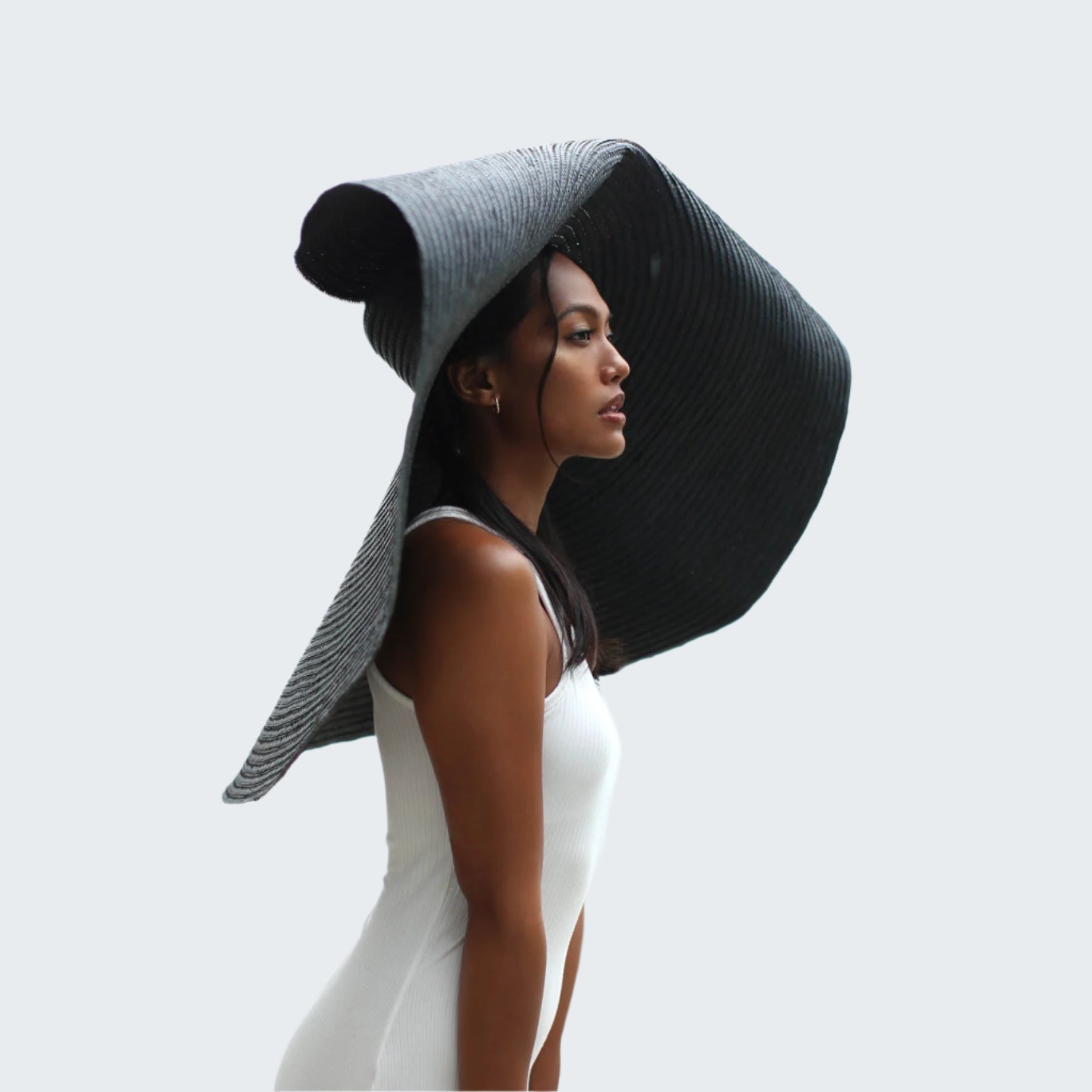 Woman wearing a large black sun hat with a blurred background