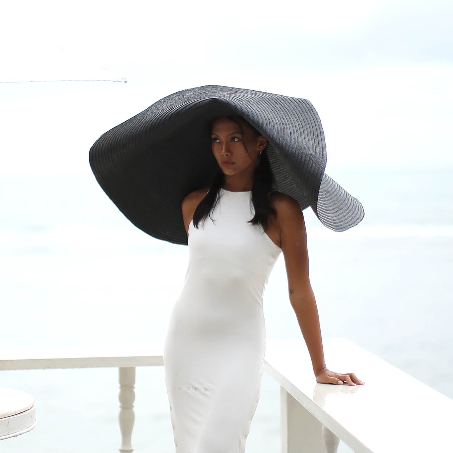 Woman wearing a large black and white striped hat against a light background