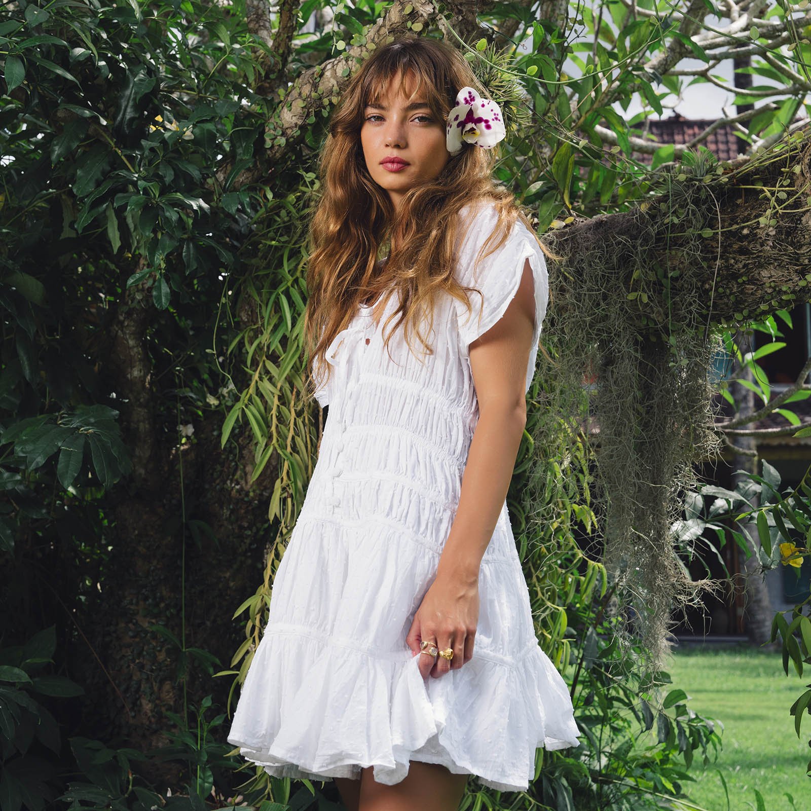 Woman in a white dress standing among greenery