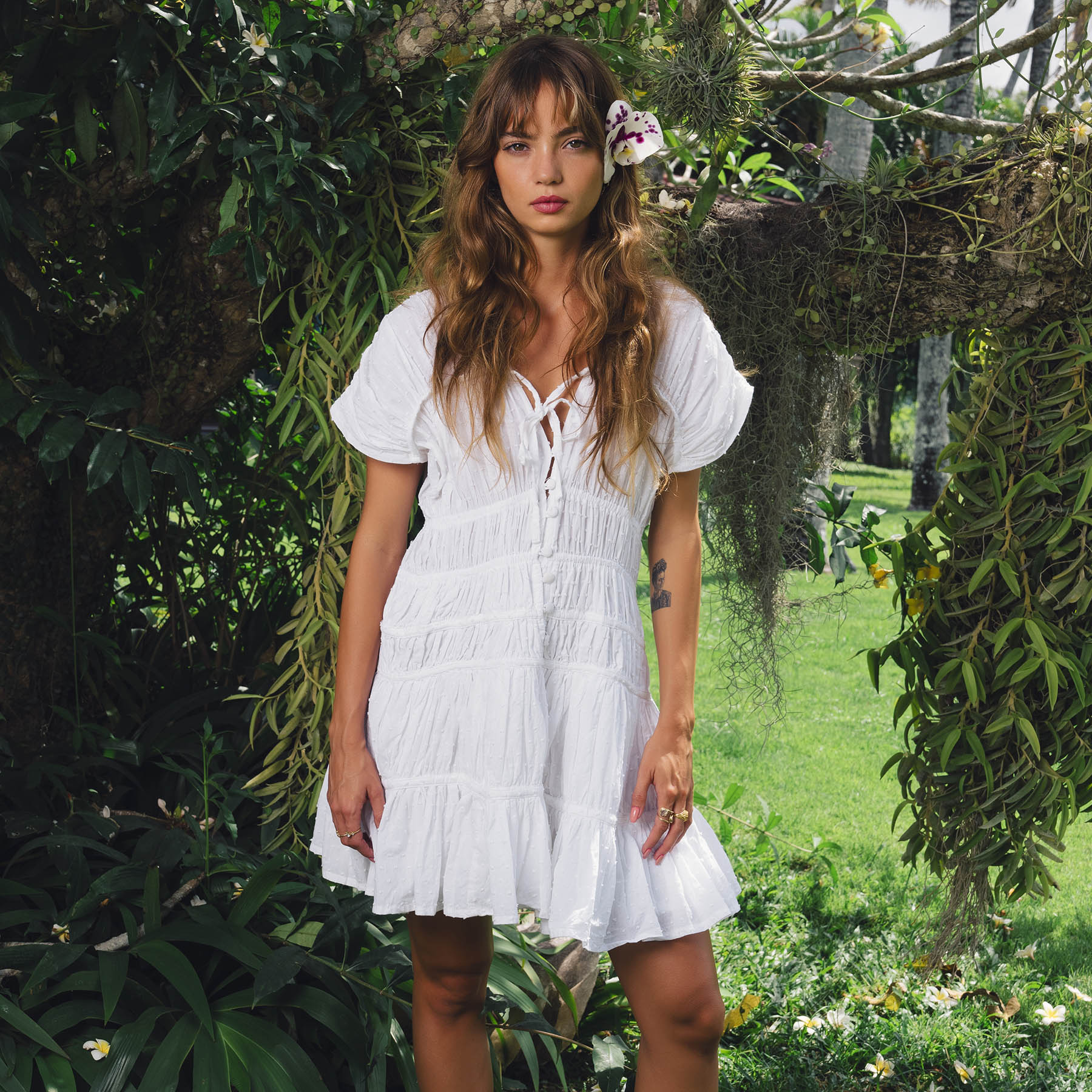 Woman in a white dress standing in a lush green garden
