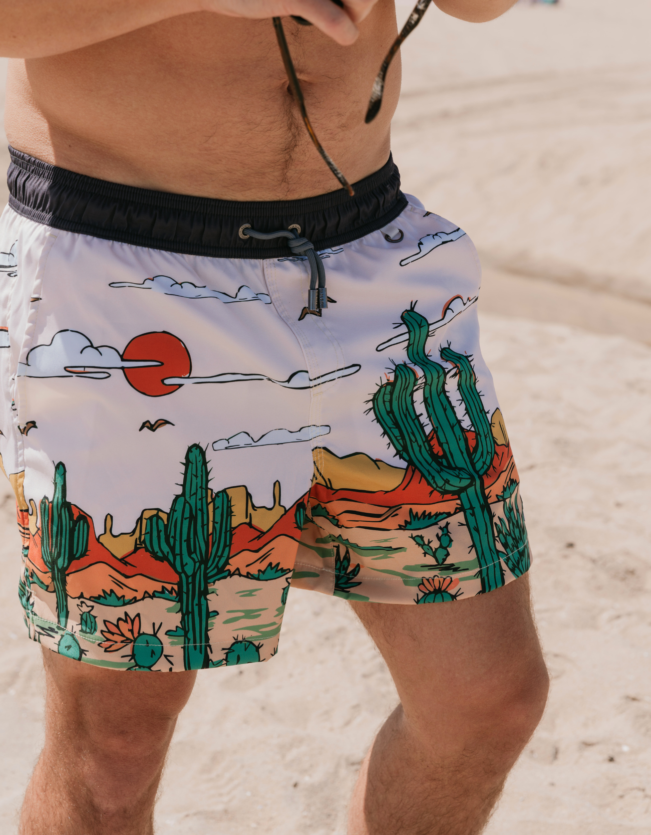 Person wearing a swimsuit with a desert-themed design on a sandy background
