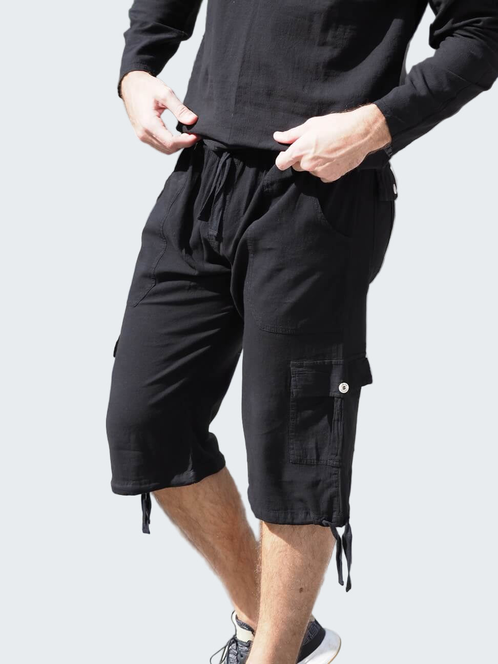 Person wearing black cargo shorts and a black long-sleeve shirt on a crosswalk.