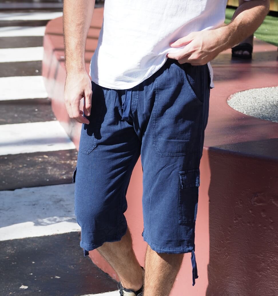 Person wearing blue cargo shorts and a white shirt on a street.