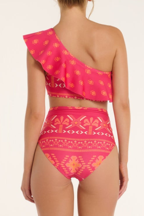 Woman wearing a pink patterned one-shoulder bikini set on a white background