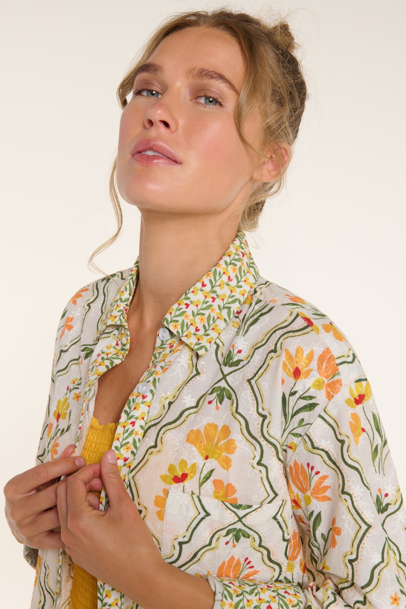 Woman wearing a floral patterned shirt against a white background