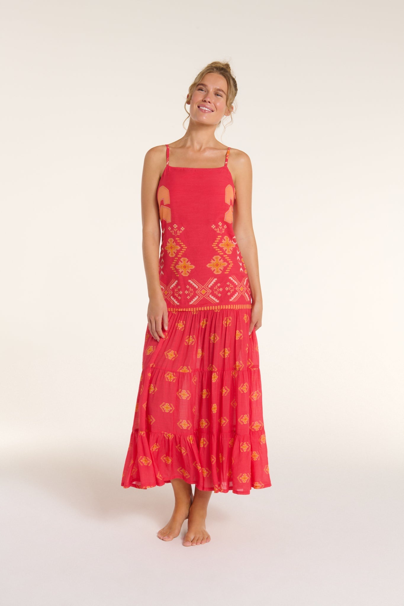 Woman wearing a red dress with yellow patterns on a white background