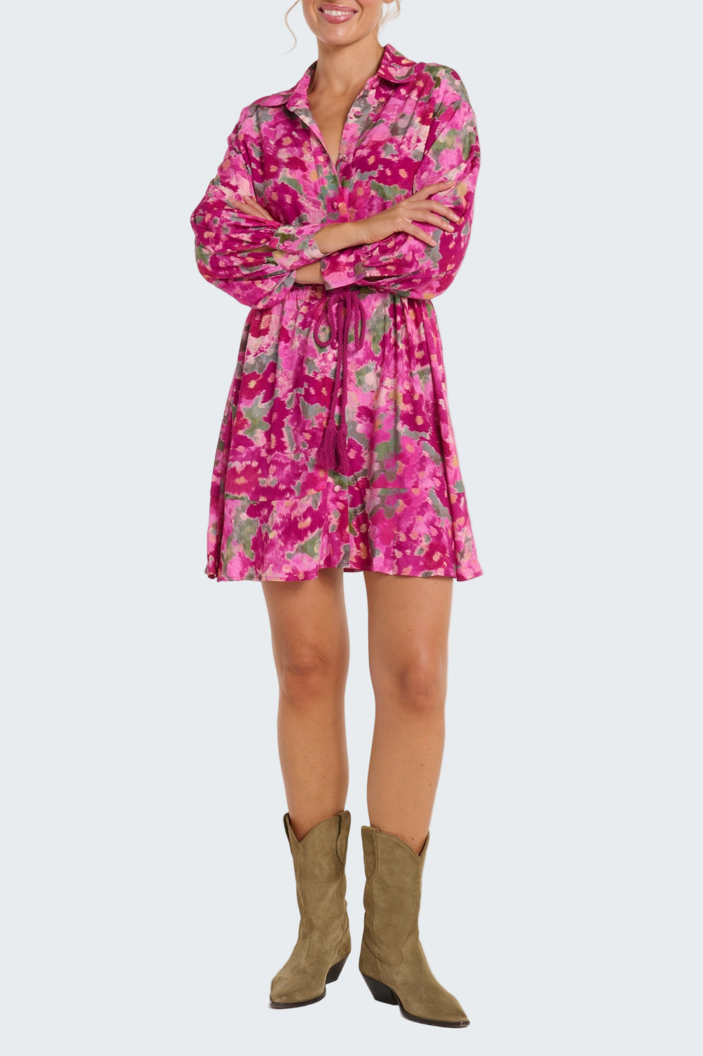 Person wearing a pink floral dress with green boots on a white background