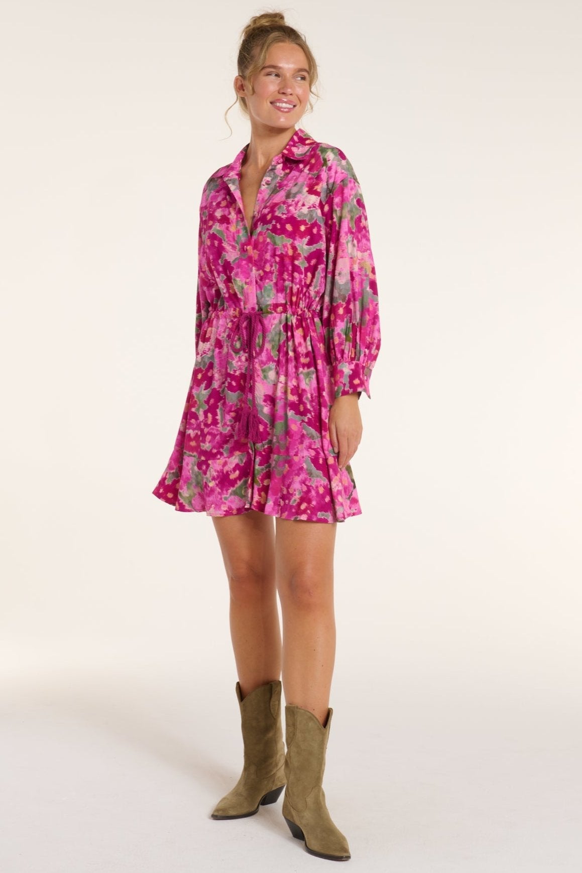 Woman wearing a pink floral dress and brown boots on a white background