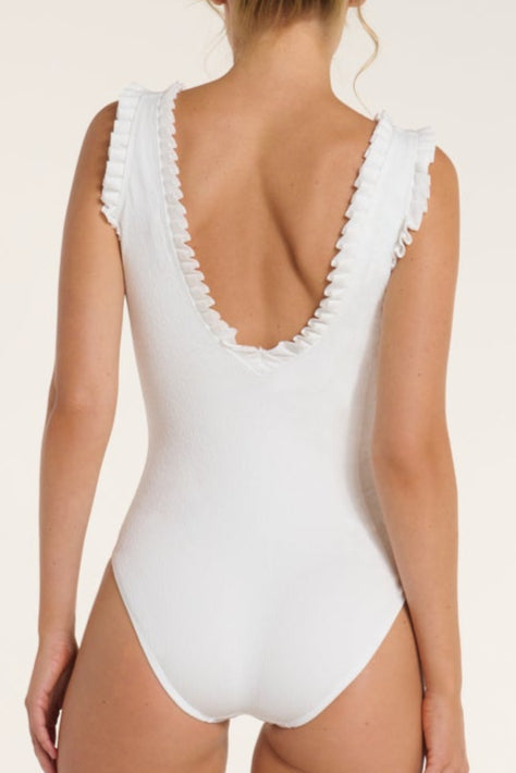 White swimsuit with ruffled details on a plain background