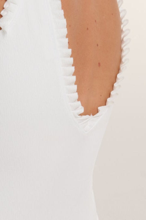Close-up of a white garment with ruffled edges on a plain background