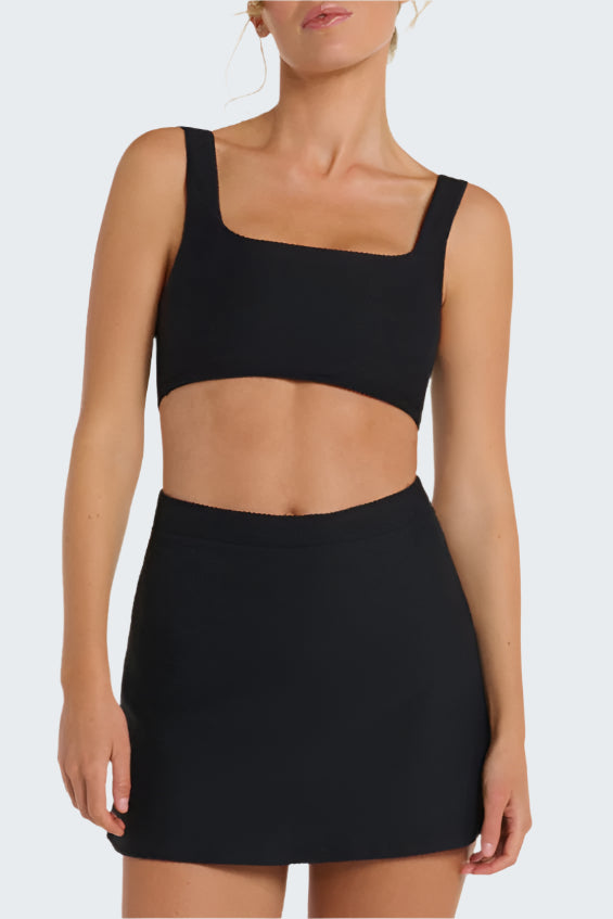 Person wearing a black crop top and skirt set on a white background