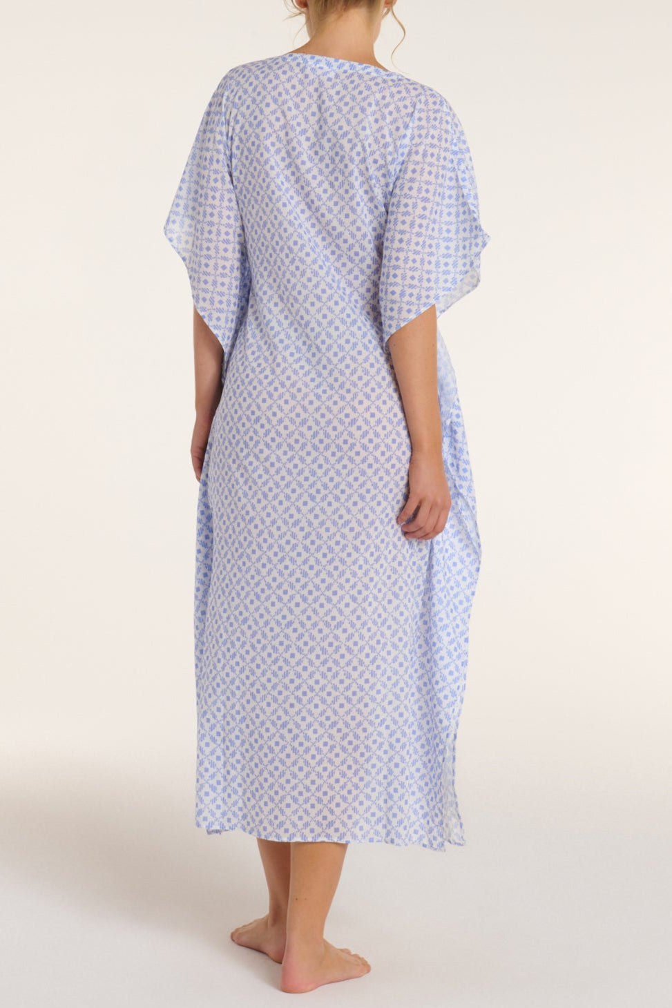 Person wearing a blue patterned hospital gown on a white background