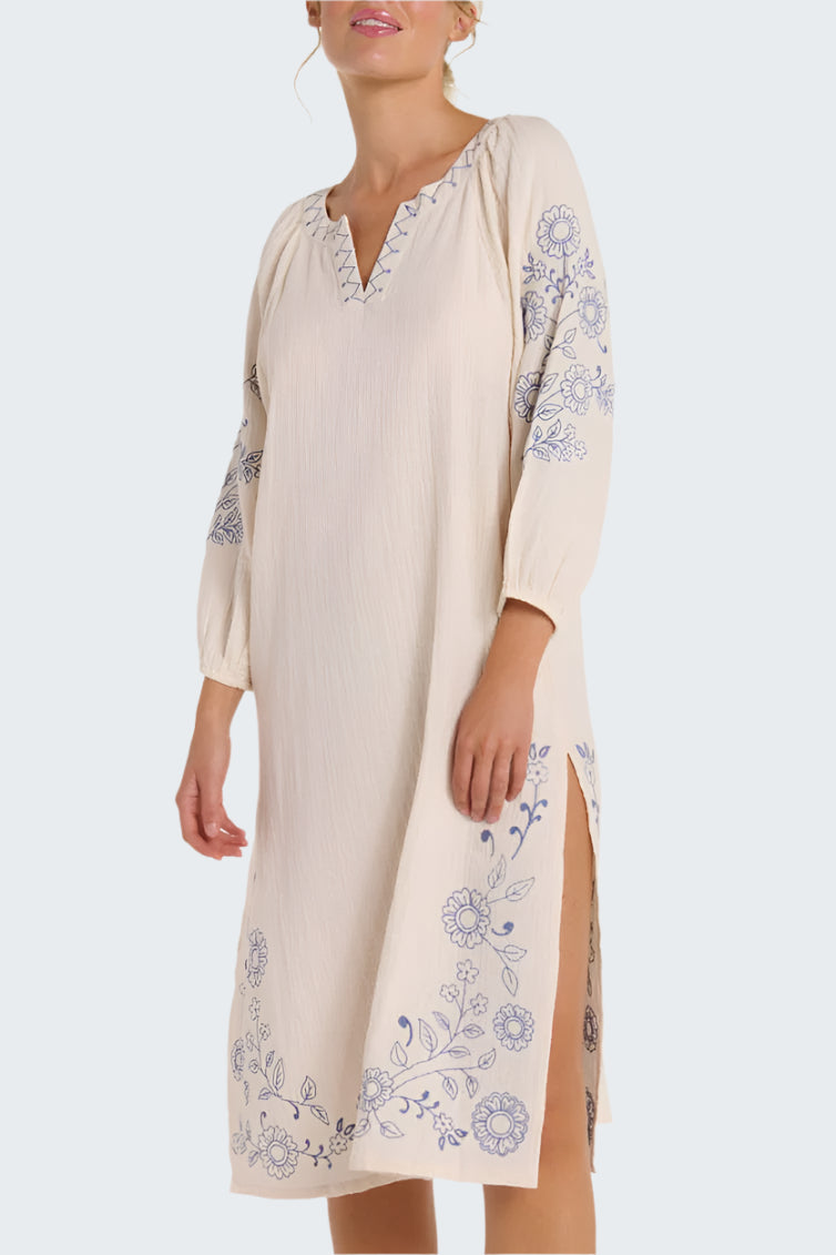 Woman wearing a beige dress with floral embroidery on a white background
