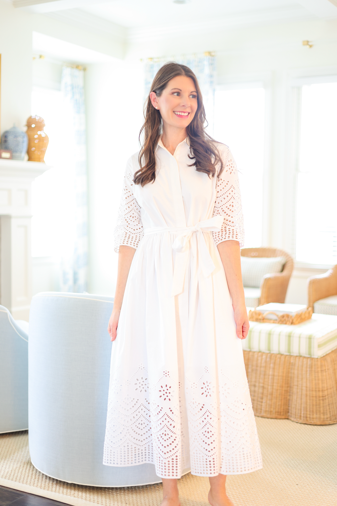 Woman wearing a white dress with lace details in a bright room.
