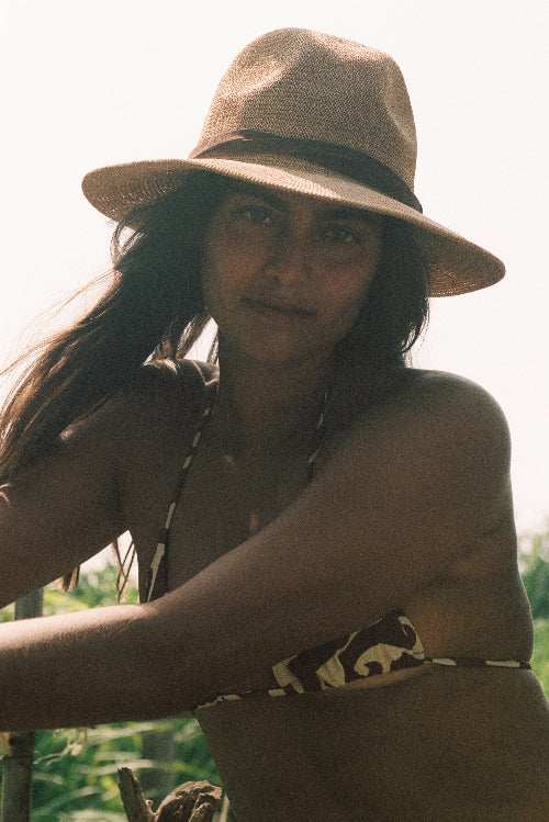 Woman wearing a straw hat and bikini in a natural setting