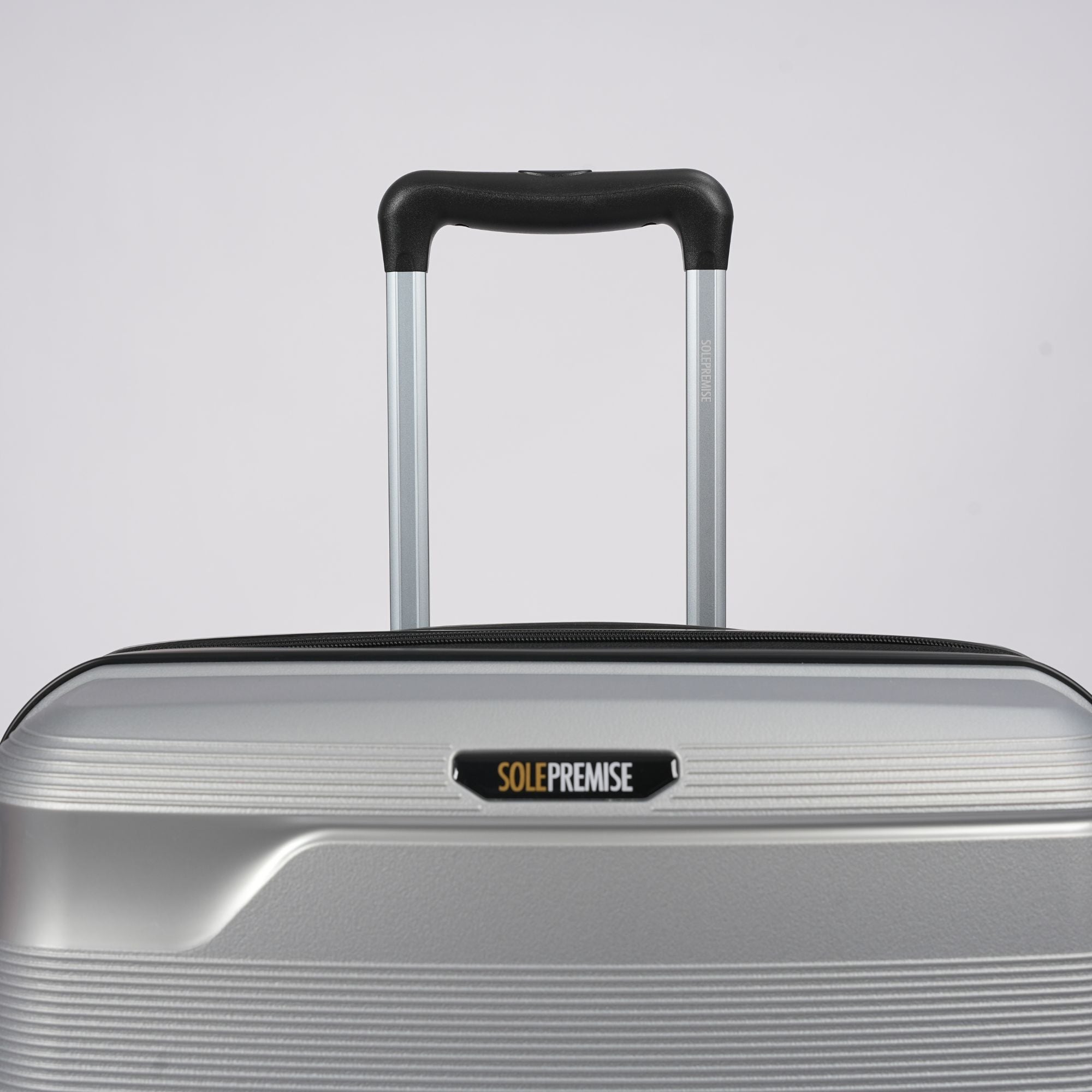 Silver suitcase with a visible brand logo on a light gray background