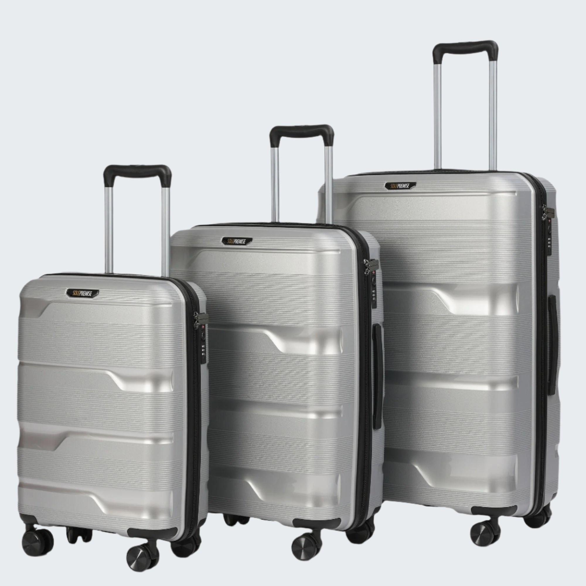 Three silver suitcases of different sizes on a light gray background