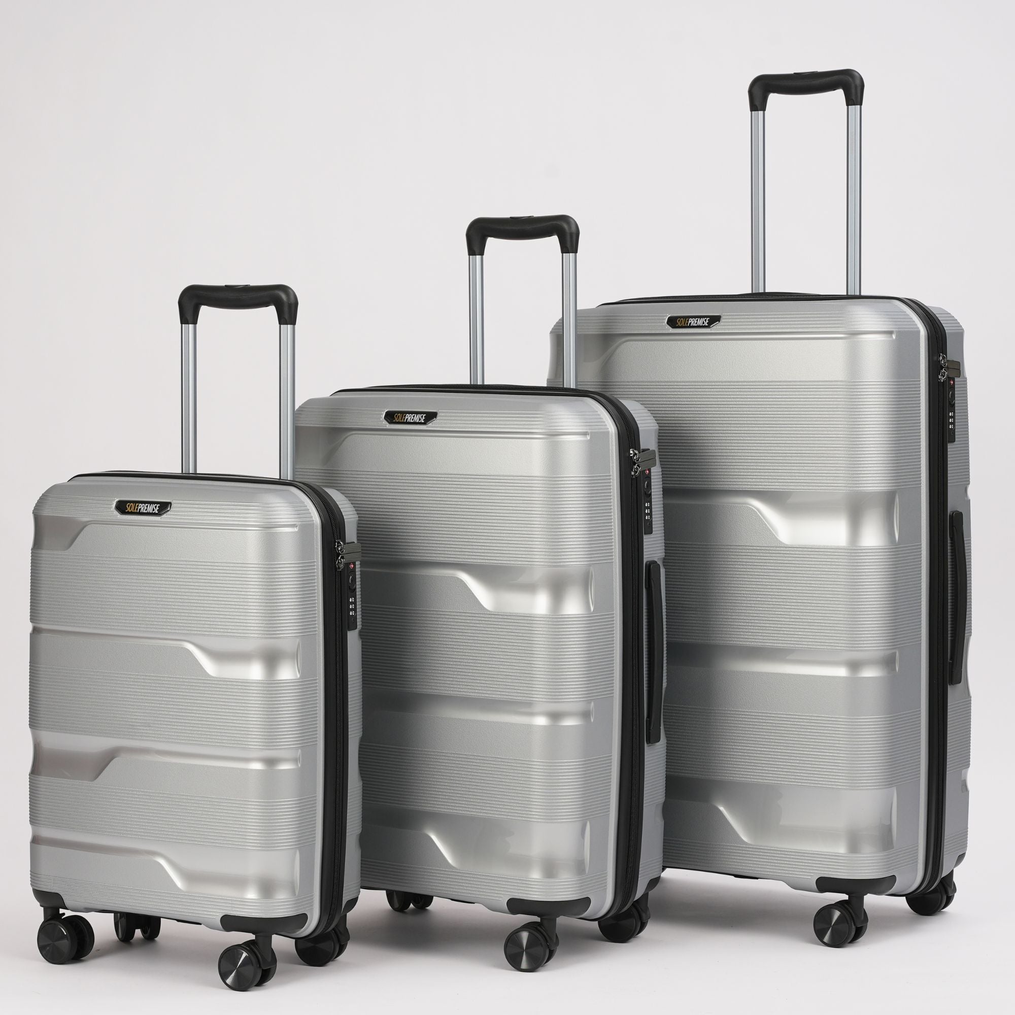 Three silver suitcases of different sizes on a light gray background