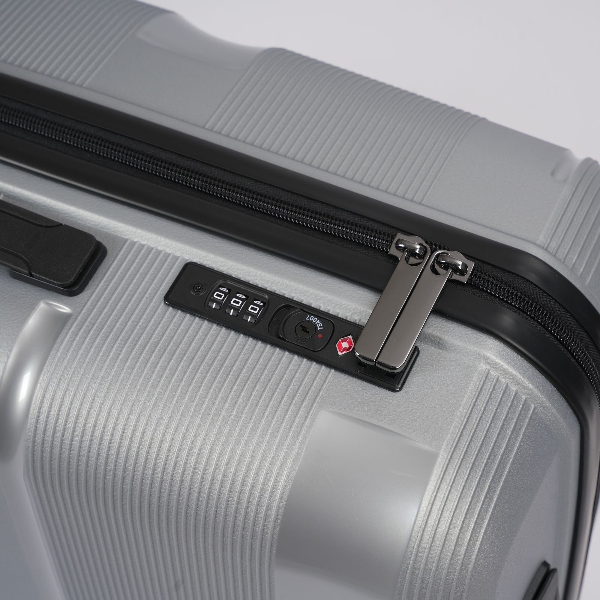 Close-up of a silver suitcase with a black combination lock on a light gray background