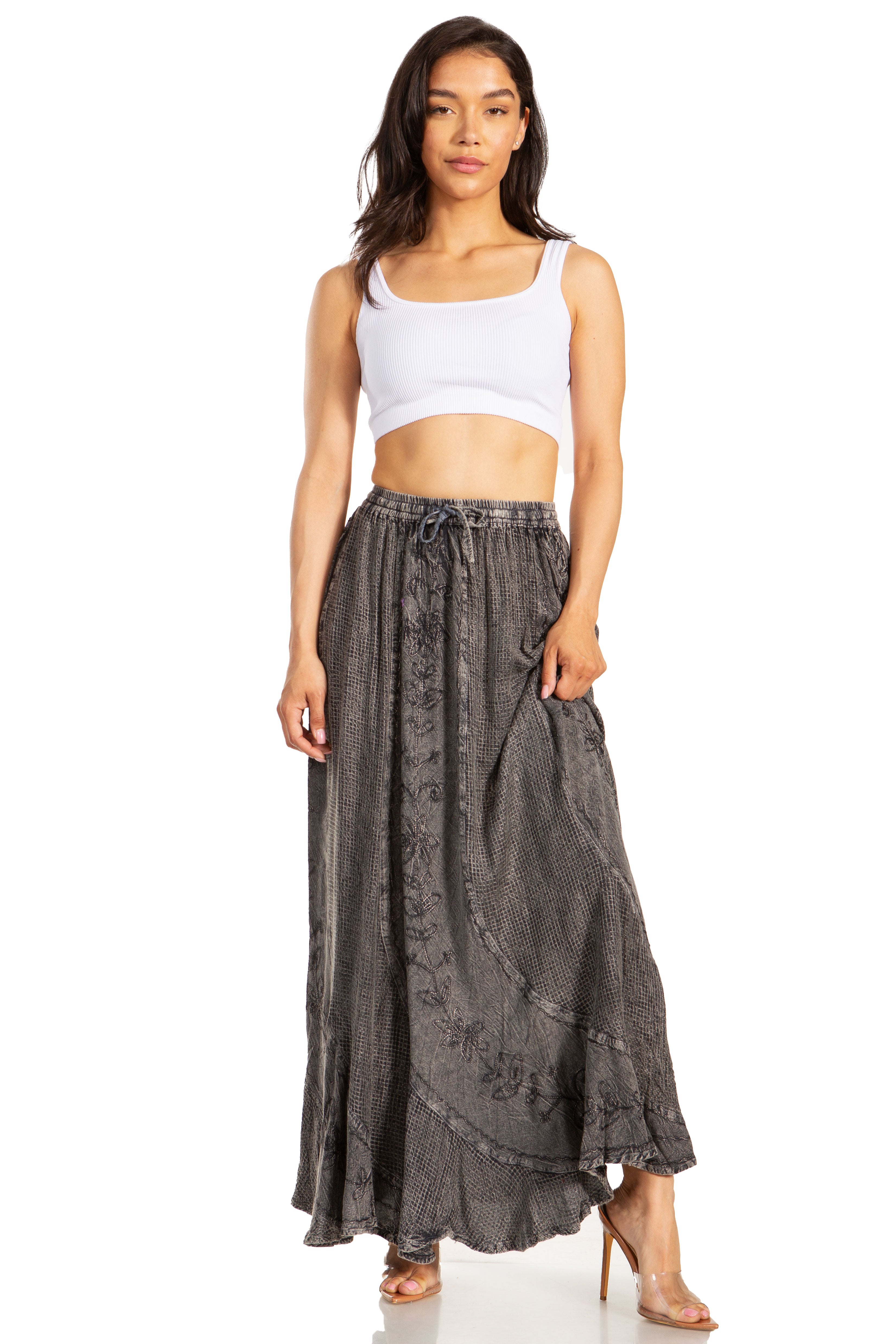 Woman wearing a white tank top and dark gray floral skirt on a white background