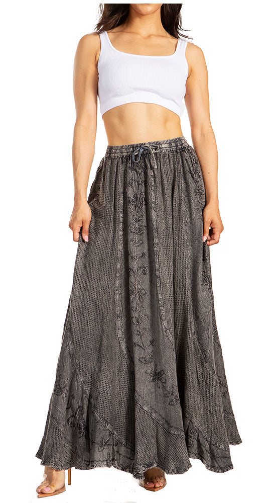 Woman wearing a white crop top and long black patterned skirt on a white background