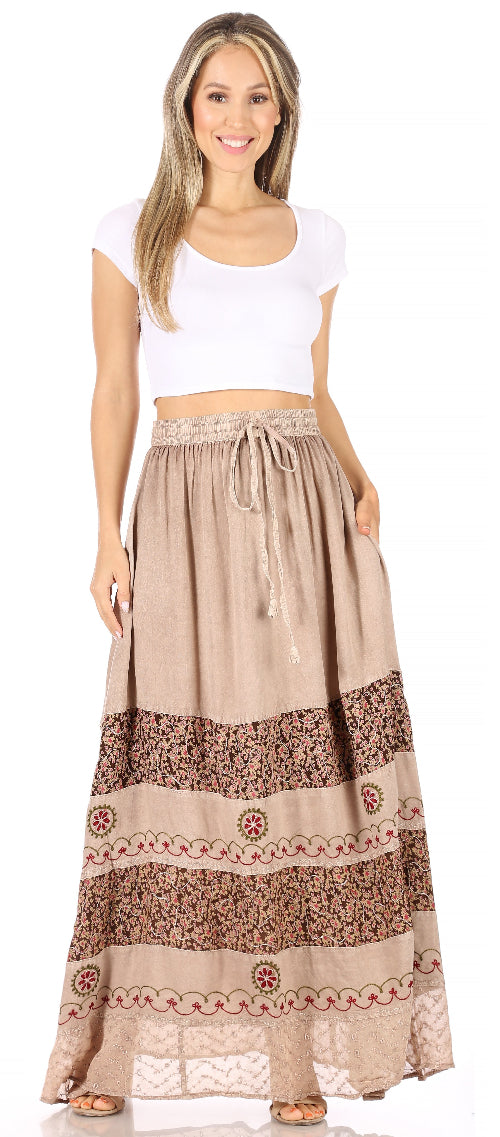 Woman wearing a long beige skirt with a patterned bottom section on a white background
