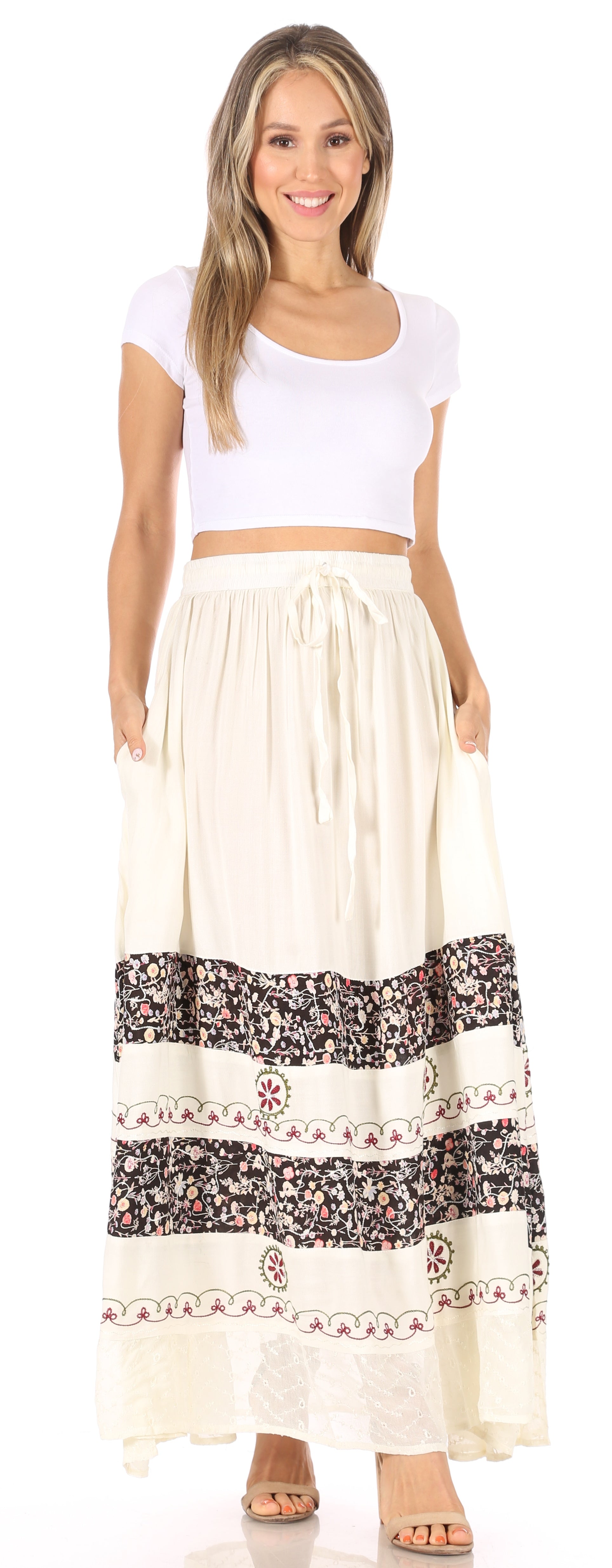 Woman wearing a white top and long beige skirt with floral patterns on a white background