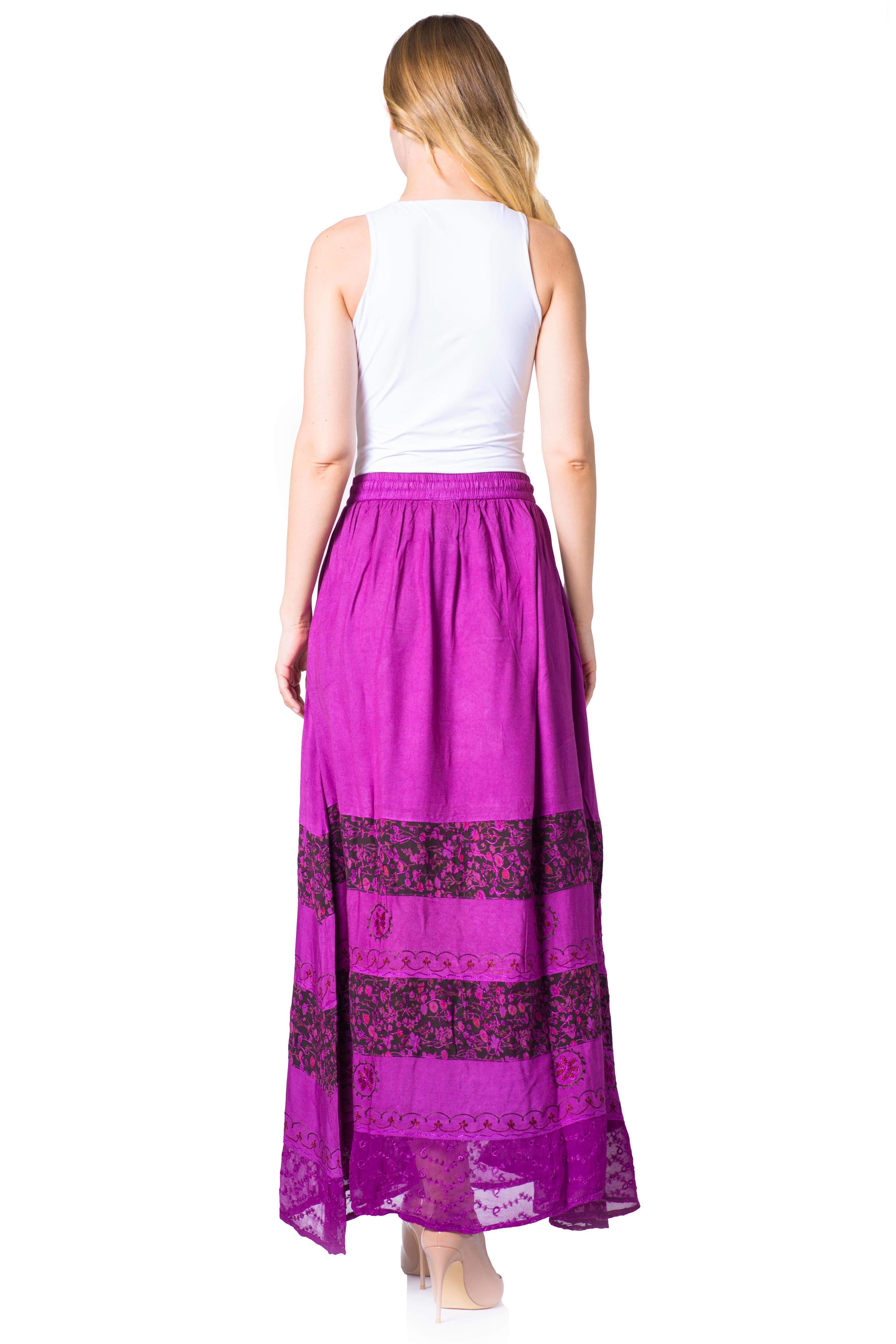 Woman wearing a white top and purple skirt with a patterned hem on a white background