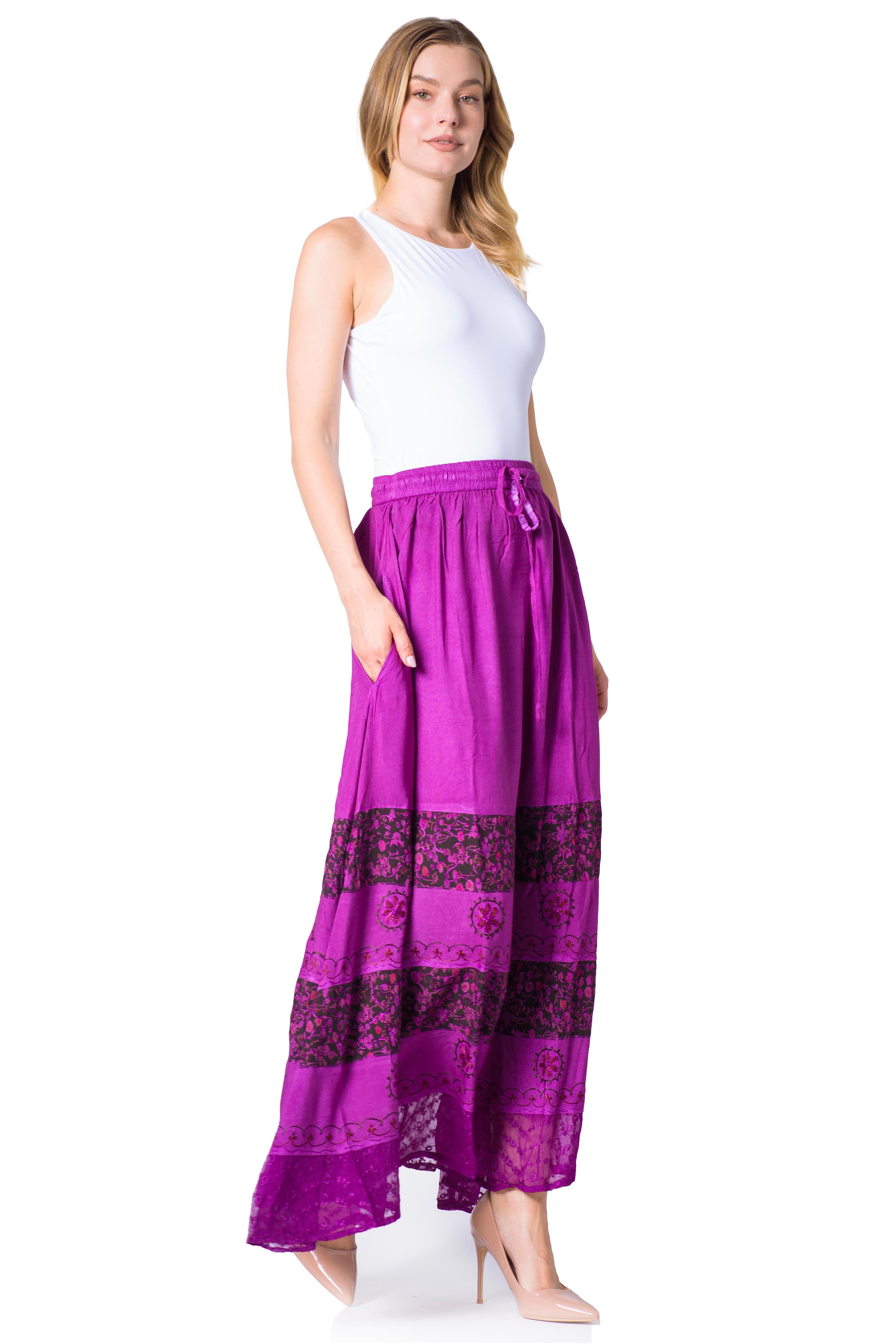 Woman wearing a white sleeveless top and purple skirt with black patterns on a white background