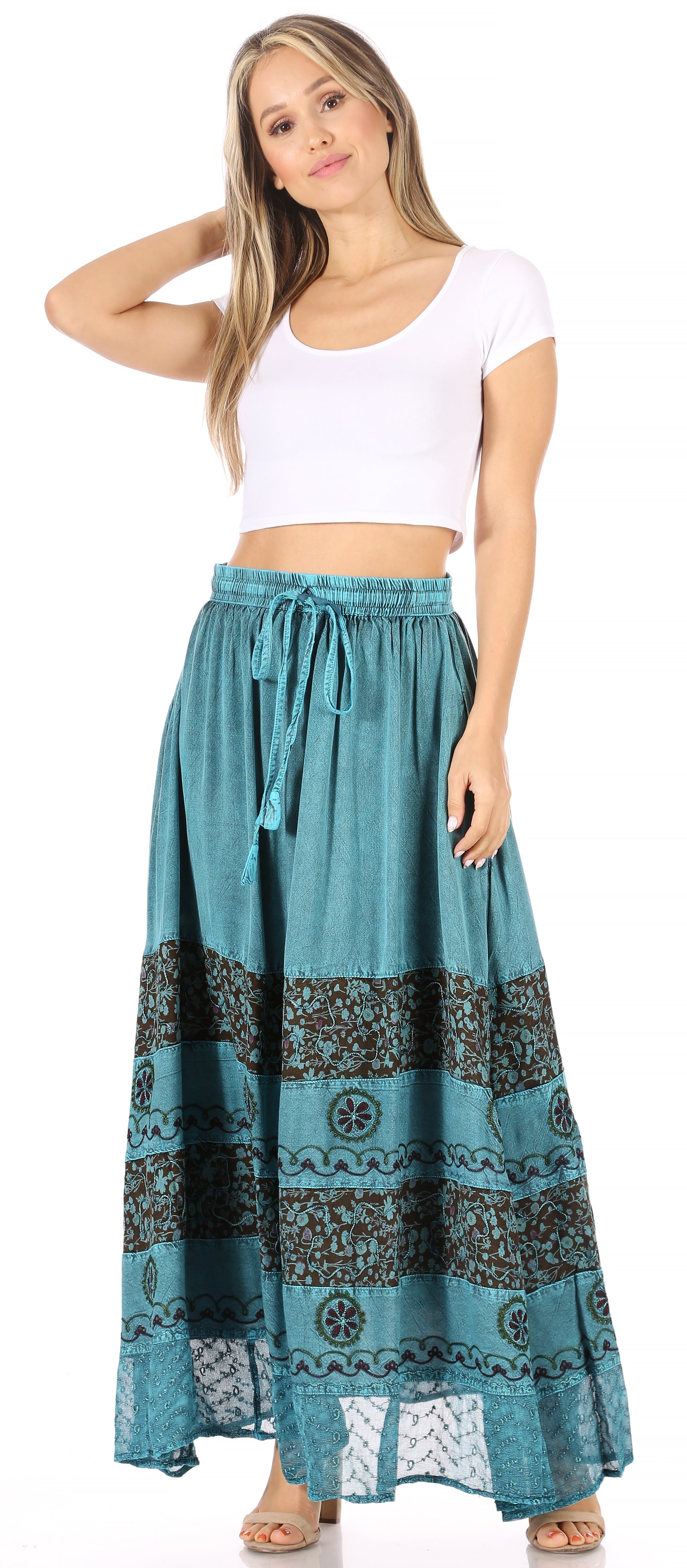 Woman wearing a white crop top and blue patterned maxi skirt on a white background