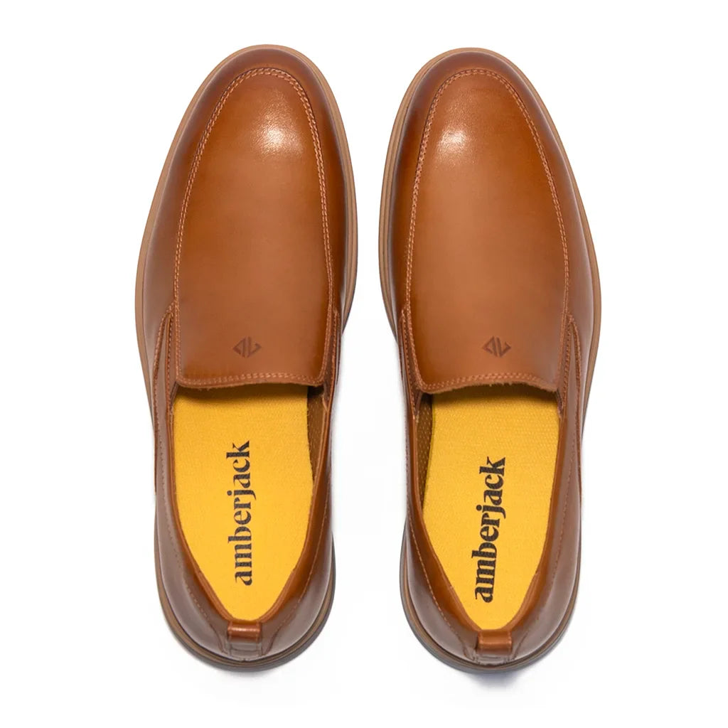 Pair of brown leather shoes with yellow soles on a white background