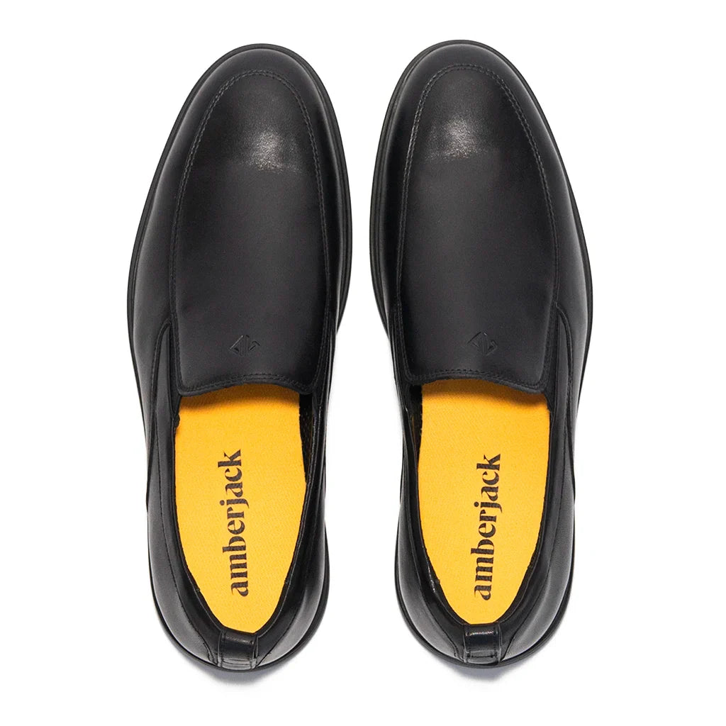 Black leather shoes with yellow soles on a white background